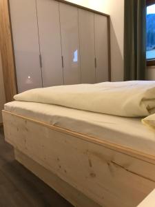 a bed with a wooden foot board on top of it at Alpenlodge Kirchbach in Kirchbach