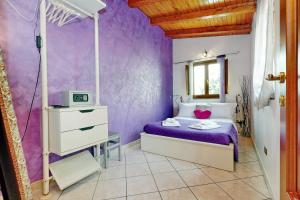 ローマにあるラグジュアリー ドムスの紫の壁のベッドルーム1室、紫のシーツが備わるベッド1台