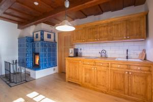 a kitchen with wooden cabinets and a blue tile fireplace at Orlí Hnízdo in Štramberk