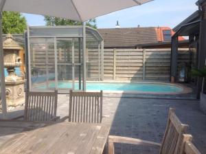 a swimming pool with an umbrella and a fountain at B&B Agnes in Vlissegem