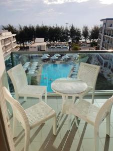 einen Balkon mit einem Tisch, Stühlen und einem Pool in der Unterkunft Grandblue condominium Room 606 in Mae Pim