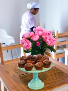 a plate of cupcakes and a vase of pink roses at B&B Policlinico Gaspare Rodolico in Catania