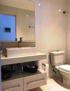 ein Badezimmer mit Waschbecken, Toilette und Spiegel in der Unterkunft Temporada Praia de Palmas SC in Governador Celso Ramos
