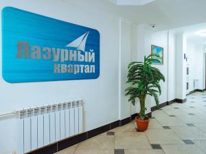 ein blaues Schild an einer Wand im Flur mit einer Pflanze in der Unterkunft Apartment on Sarayshyq in Astana