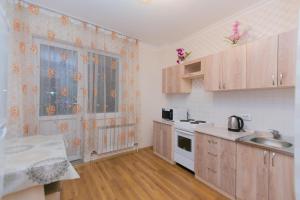eine kleine Küche mit Holzschränken und einem Waschbecken in der Unterkunft Apartment on Sarayshyq in Astana