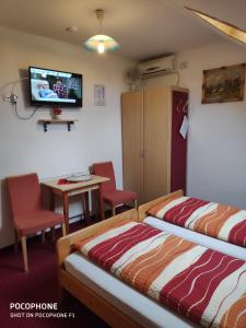 a room with two beds and a tv on the wall at Herkules Panzió in Nagykanizsa