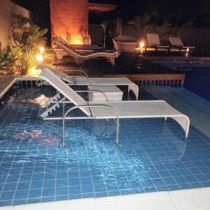 a swimming pool with two chairs and a table in the water at Casarão da Ferradura B&B in Búzios