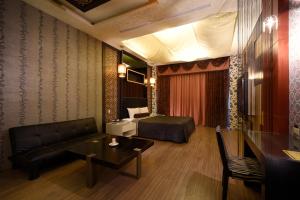 um quarto com uma cama, um sofá e uma mesa em Sun Garden Motel em Kaohsiung