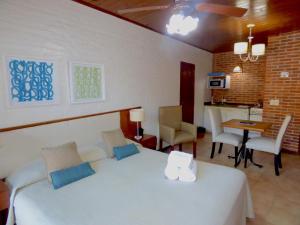 a bedroom with a white bed and a dining room at Cariló Paradise Apart Hotel & Spa in Carilo