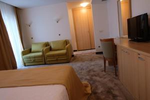 a hotel room with a bed and a couch and a television at Hotel Flores in Poreč