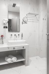 a white bathroom with a sink and a shower at Solun Hotel & SPA in Skopje