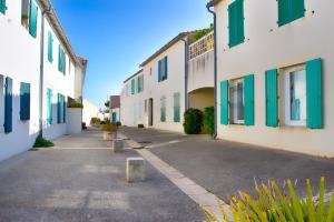 an empty street with white buildings with green shutters at Clos Vauban in Saint-Martin-de-Ré