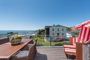 a wooden table and chairs on a deck with a view of the ocean at Bel Etage in der Villa Amelie am M in Sassnitz