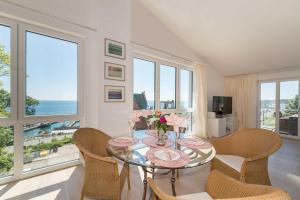 a dining room with a glass table and chairs and windows at Bel Etage in der Villa Amelie am M in Sassnitz +13 photos