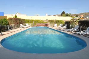 uma grande piscina azul com cadeiras num quintal em Casa Nostra Hotel em Villa Carlos Paz