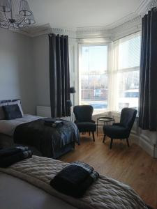 a bedroom with two beds and chairs and a window at William Wallace Apartment in Stirling