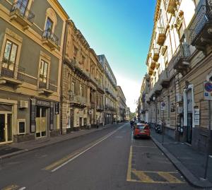 un coche rojo conduciendo por una calle con edificios en B&B Da Rì, en Catania
