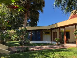 a house with a palm tree in front of it at La Casa de Cariari Al Golf in Heredia