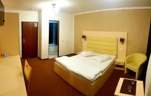 クラヨーヴァにあるMBI Travel Innのベッドと椅子付きのホテルルーム