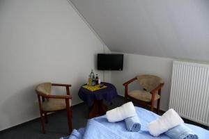 LüssowにあるLandpension Strenzのベッド1台、椅子2脚、テーブルが備わる客室です。
