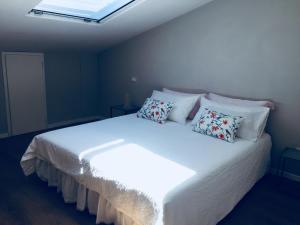 una camera da letto con un grande letto bianco con cuscini di Cocciopestorooms a Marina di Massa