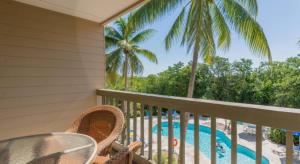 balcón con mesa y sillas y piscina en Coconut Mallory Resort and Marina en Cayo Hueso