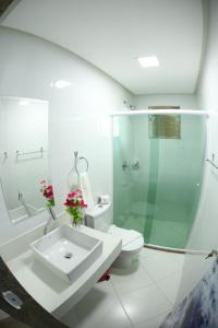a bathroom with a toilet and a sink and a shower at Gabrielly Praia Hotel in Guaibim
