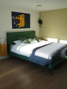 a bedroom with a large bed with a green headboard at B&BbyBerry in Lieshout