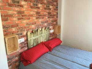 a brick wall with a bed with a red pillow at Monkey Room in La Línea de la Concepción