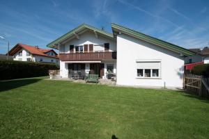 a white house with a green lawn in front of it at Ferienwohnung am Chiemsee in Bernau am Chiemsee
