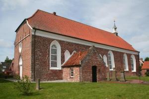 a large brick church with a red roof at Kiebitznest in Krummhörn