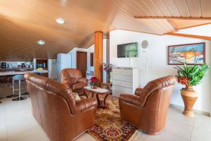 een woonkamer met lederen stoelen en een televisie bij Apartment lucy in Arco da Calheta