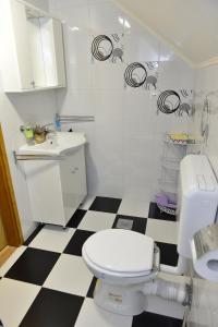 uma casa de banho com um WC branco e um piso xadrez preto e branco em Apartmani Miščević em Josipdol
