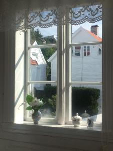 een raam met een vaas op een vensterbank bij Reinertsenhuset in Skudeneshavn
