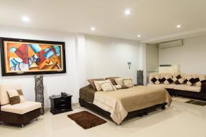 - une chambre avec un lit, un canapé et un tableau dans l'établissement Hotel El Aeropuerto, à San José del Guaviare