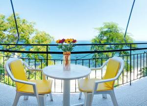 uma mesa com duas cadeiras e um vaso de flores numa varanda em Empress Corfu em Perama mais 31 fotografias