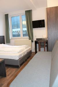 a hotel room with two beds and a table and a desk at Pionier Hotel Hamburg Wandsbek in Hamburg