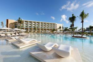 a resort swimming pool with white chairs and palm trees at Grand Palladium Costa Mujeres Resort & Spa - All Inclusive in Cancún