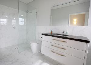uma casa de banho branca com um lavatório e um chuveiro em Lot113 Vineyard Accommodation em Upper Swan