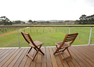 dos sillas sentadas en una terraza con un campo en Lot113 Vineyard Accommodation, en Upper Swan