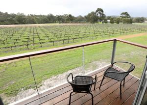 two chairs sitting on a deck looking at a vineyard at Lot113 Vineyard Accommodation in Upper Swan