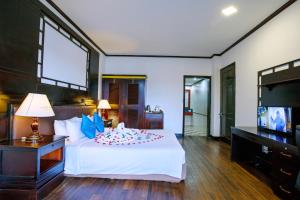 a bedroom with a white bed and a television at River Beach Resort & Residences in Hoi An