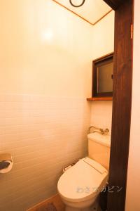a bathroom with a white toilet and a mirror at Lucky Duck Cabin in Akakura