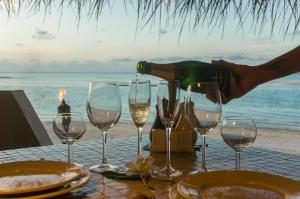 a person is pouring wine into wine glasses on a table at Ninamu Resort in Tikehau