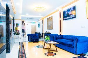 a living room with blue couches and a table at Al Afiah Hotel in Bandar Seri Begawan