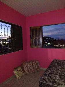 a bedroom with pink walls and a bed and a window at Guaraná da Cláudia in Santarém