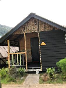 a small house with a black roof and a porch at Beach Shack Chalet - Garden View Aframe Big Unit in Tioman Island
