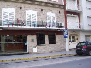 a building with flags on a balcony and a car parked on the street at Apolo Atlantis in Mar del Plata