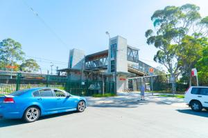 um carro azul estacionado em frente a um edifício em Panania Hotel Sydney em Panania