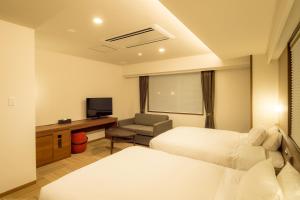 una camera d'albergo con due letti e una televisione di Hotel Munin Furano a Furano